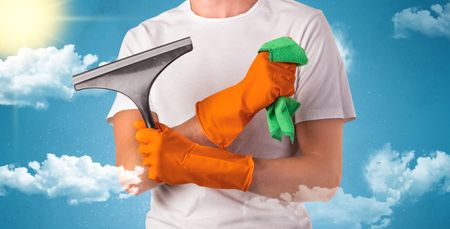 Sunny and cloudy concept with male housekeeper and orange gloves on his hand