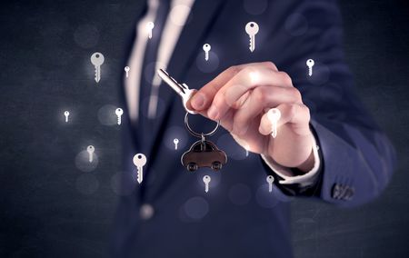 Businessman in suit holding keys with keys graphics around and dark background
