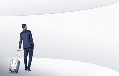 Businessman with back walking in a white waiting room with empty walls around
