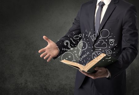 Businessman holding book with doodle drawings and signs.