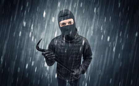 Burglar in action in black clothes with rainy concept.