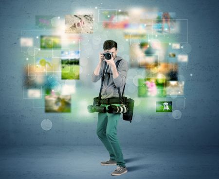 A young amateur photographer with professional camera equipment taking picture in front of blue wall full of faded pictures and glowing lights concept