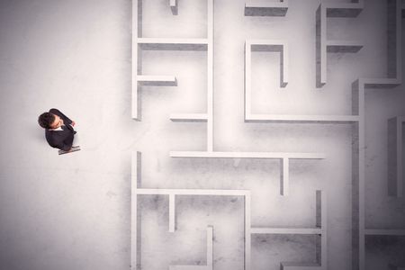 Confused businessman standing at a maze wall with grungy background