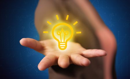A creative businessman has a great bright idea illustrated by holding a drawn light bulb in the hand concept