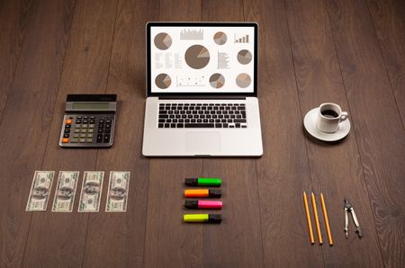 Pie chart graph icons and symbols on laptop screen with office accessories