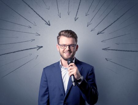 Businessman speaking into microphone with arrows pointing towards his head