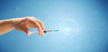 Female doctor hand holding syringe with blue background and shine