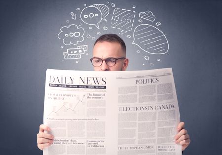 Puzzled young businessman reading daily newspaper with speech bubbles above his head