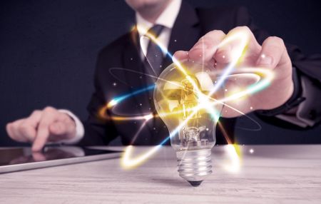 A classy businessman holding a colorful light bulb with shining circles in front of dark background concept.