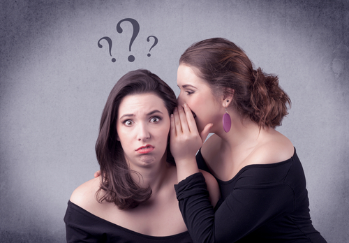 A teenager girl looking confused with drawn question marks above the head, while a girlfriend whispers something in her ear concept.