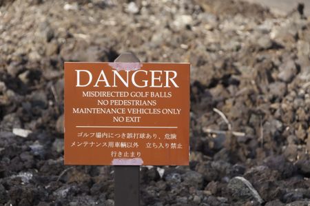 Warning sign in English and Japanese posted in lava field on golf course in Hawaii