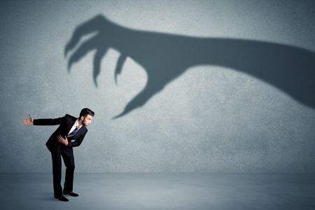Business person afraid of a big monster claw shadow concept on background