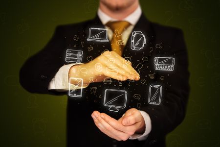 Businessman holding icons related to devices and communication