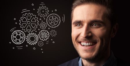 Portrait of a young businessman with rotating gears next to him on a dark background