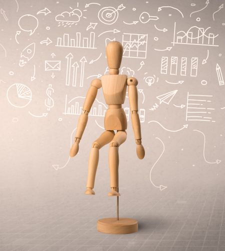 Wooden mannequin posed in front of a greyish background with white scribbled data around him