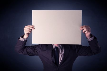 Young businessman hiding behind a blank piece of paper