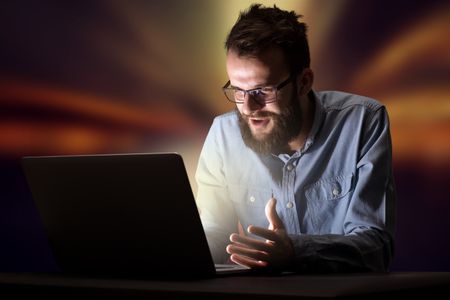 Young handsome businessman working late at night in the office with warm lights in the background