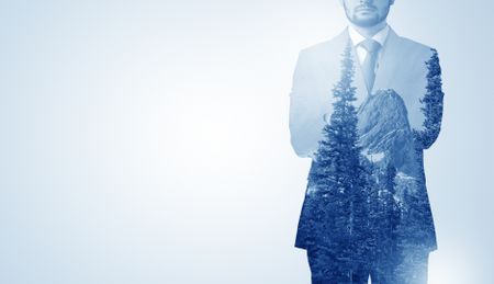 Young businessman standing and meditate with trees on the background 