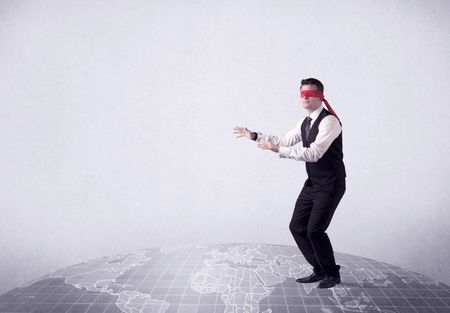 Young blindfolded businessman steps on a grey world map