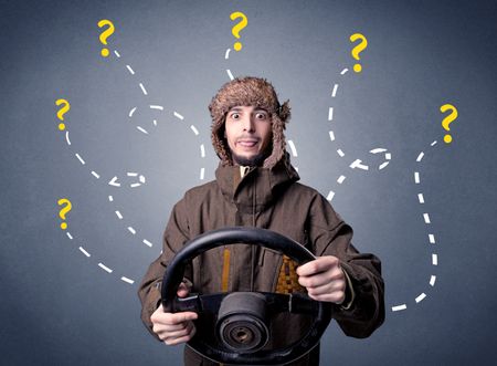 Young man holding black steering wheel with question marks around him