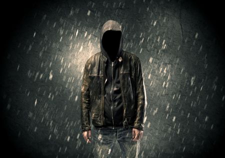 A faceless misterious man in hoodie and leather jacket standing in the dark with a visible silhouette concept