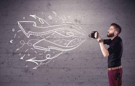 A hipster guy opening his point of view through looking a vintage camera concept with illustratied drawn arrows on urban wall