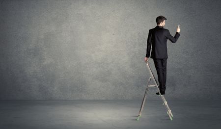 A man standing on ladder drawing with chalk in his hand on clear wall pattern background