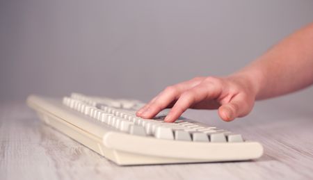 Close up of hand pressing keyboard buttons on desk