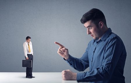 Young professional businessman being angry with an other miniature businessman 