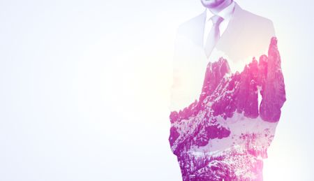 young-businessman-suit-standing-sunny-snowy-686565391 Young businessman in suit standing with sunny snowy mountain and trees graphic.