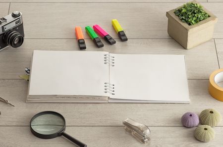 Empty notebook on wood floor with office tools nearby