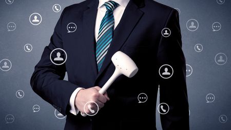 Thoughtful businesman holding tool with communication symbols around
