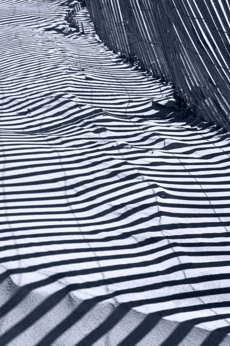 Pattern of shadows of beach fence on sand