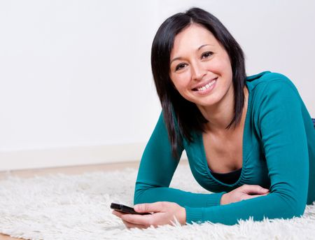 Woman at home lying on the floor with a cell phone