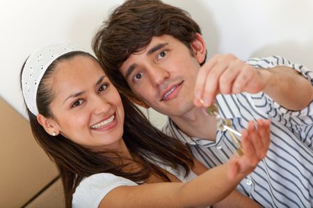 Loving couple holding keys to a new house while moving