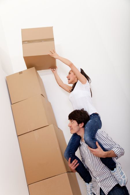 Couple piling cardboard boxes while packing for moving