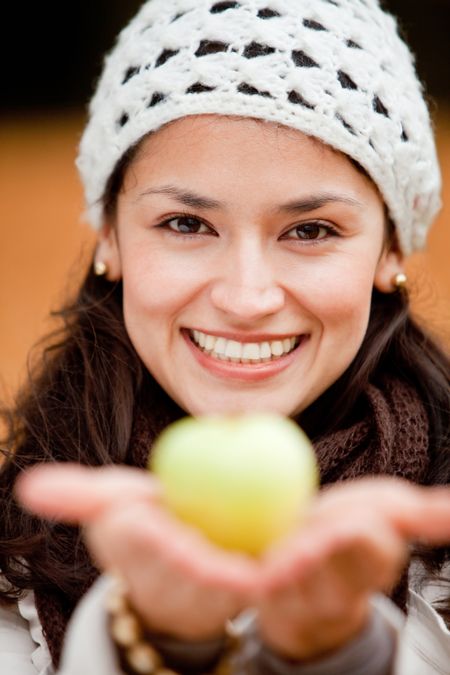 Beautiful autumn woman holding an apple and smiling