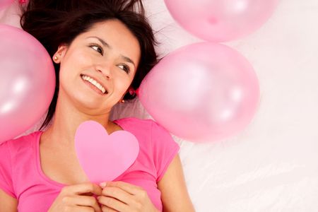 Woman holding a heart with pink balloons around her isolated