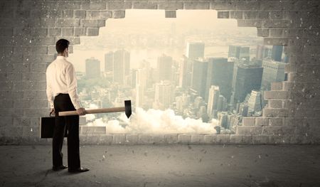 Business man hitting wall with hammer on city view background