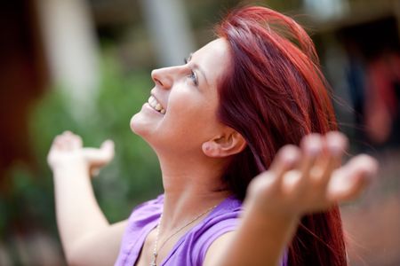Relaxed woman with arms open outdoors and smiling