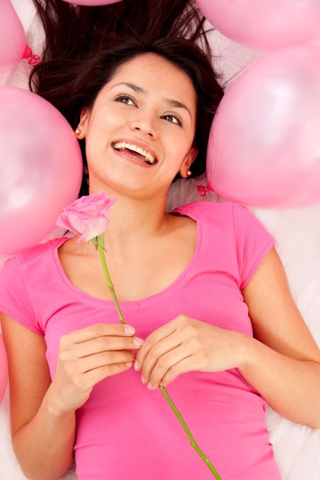 Woman holding a pink rose with ballons around her