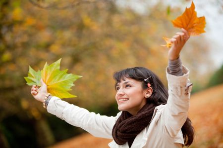 Autumn woman portrait smiling outdoors holding leaves