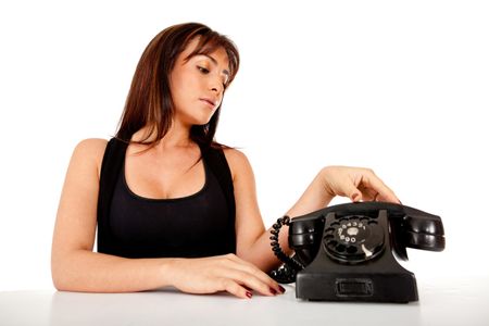 Woman waiting a call next to an old style phone - isolated over white