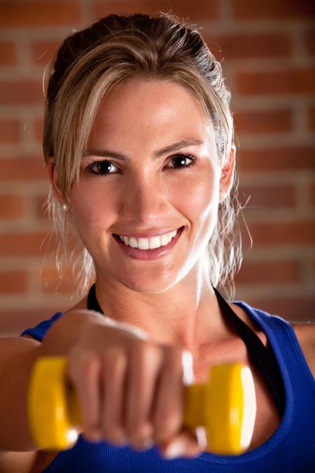Beautiful woman exercising with free-weights and smiling