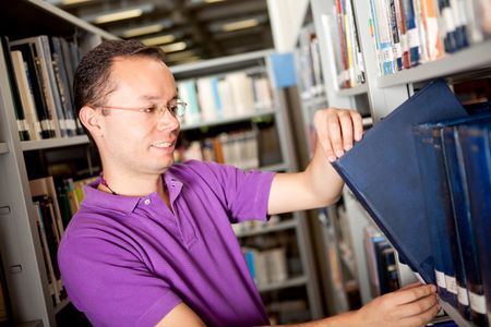 Male student at the library looking for a book