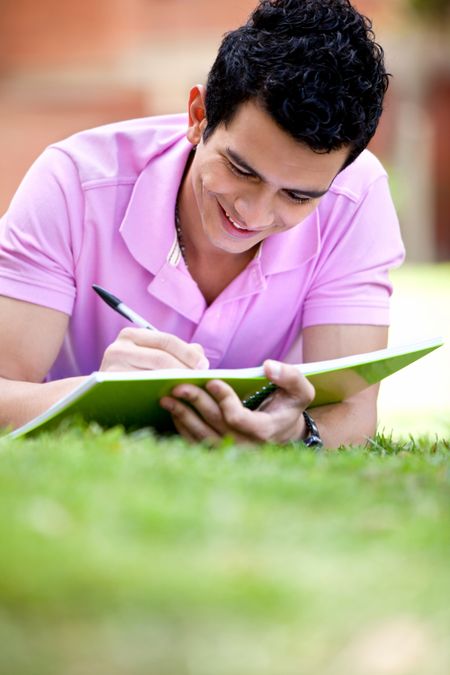 Casual guy studying outdoors lying on the floor