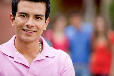 Casual man smiling outdoors with a group behind him