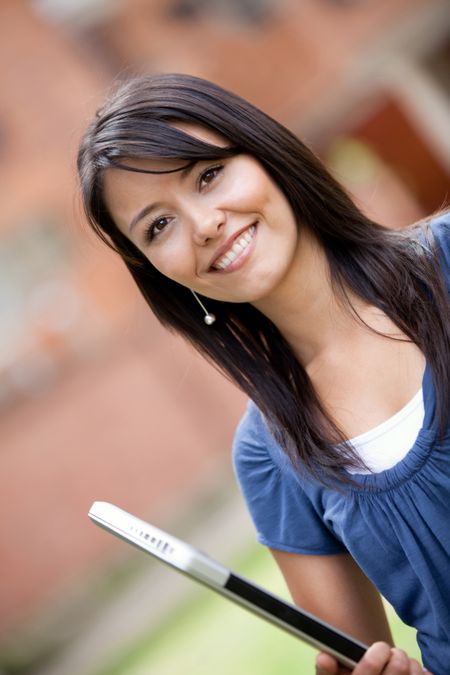 Girl holding a laptop computer outdoors and smiling