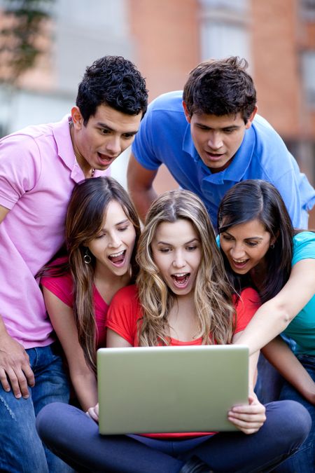 Surprised group of friends looking at a laptop outdoors
