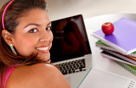 Happy female student with a laptop and notebooks
